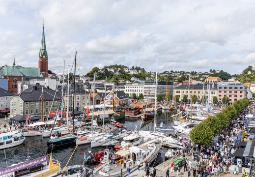 Oversiktsbilde over Arendal sentrum (indre Pollen), med båter og et folkehav av mennesker.