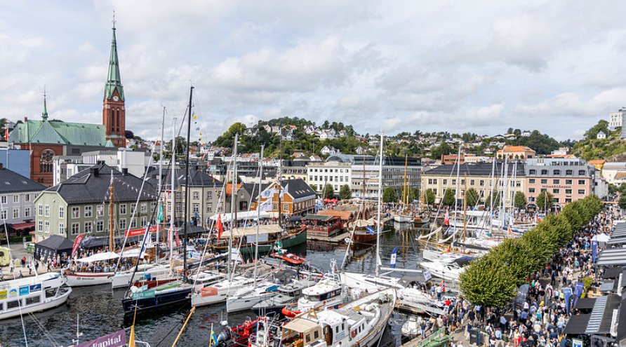 Oversiktsbilde over Arendal sentrum (indre Pollen), med båter og et folkehav av mennesker.