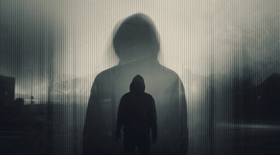 Silhuett av en mann med hettegenser, stående med ryggen mot kamera. Dobbel eksponering av personen, en større og en mindre person plassert inni. Står alene om kvelden i et byområdet. Bilder er mørkt og i gråtoner. 