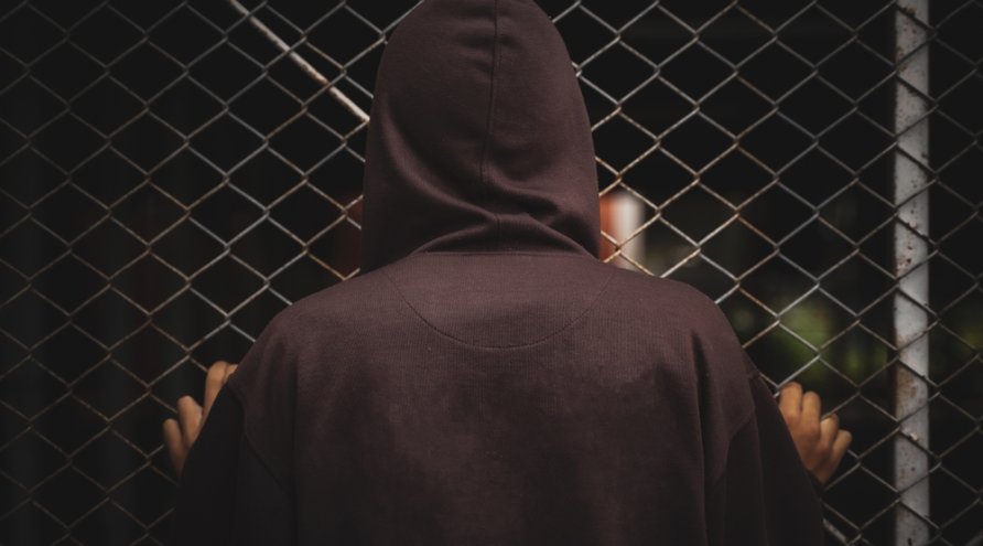 Mann med hettegenser foran netting.