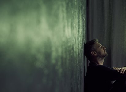 Mann lener hodet inntil en vegg