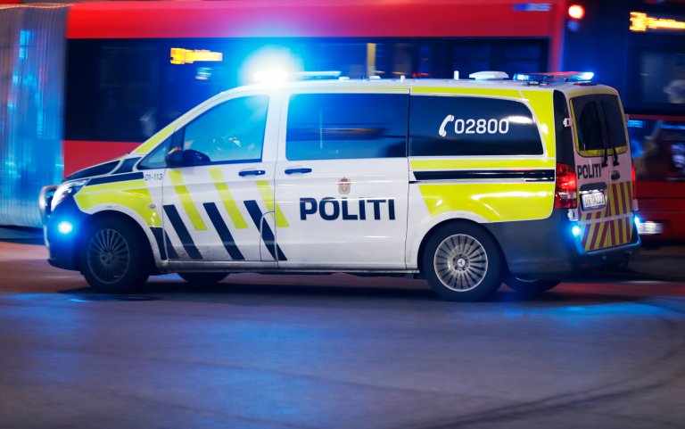 Politibil med blålys i et bybilde, politibil i fokus
