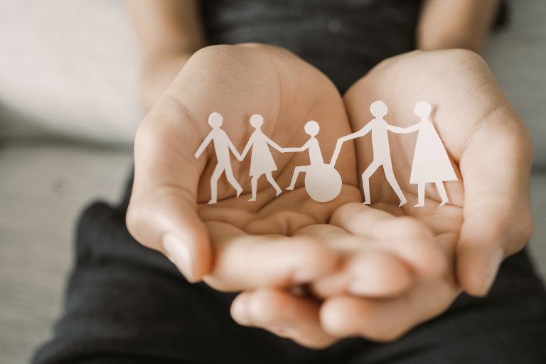 Hender som holder uklippsiluetter av familie