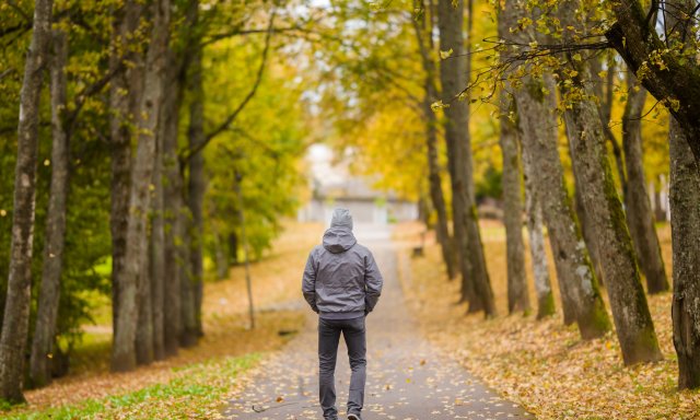 Mann går på en sti i en park med rygg mot kamera 